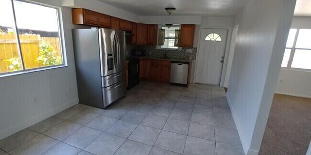 kitchen with backsplash, light tile patterned floors, a healthy amount of sunlight, and appliances with stainless steel finishes