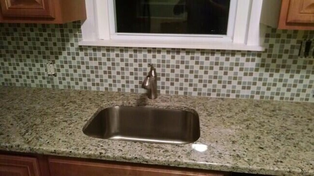 interior details featuring light stone countertops, sink, and decorative backsplash