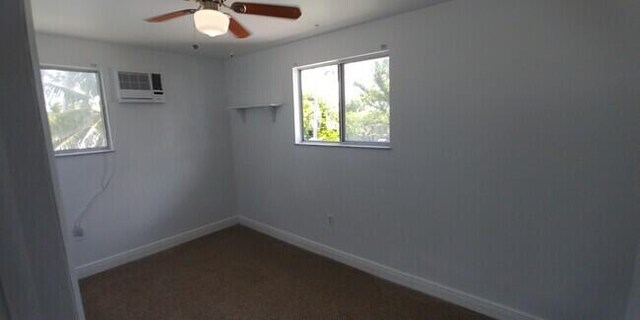 unfurnished room with an AC wall unit and ceiling fan