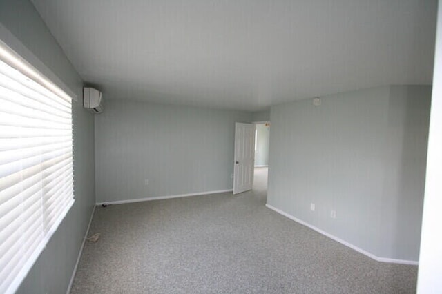 carpeted spare room featuring a wall mounted air conditioner