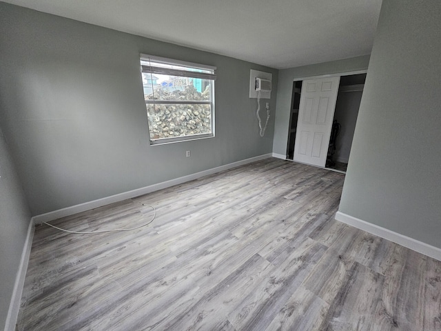 unfurnished bedroom featuring light hardwood / wood-style flooring, a closet, and a wall mounted AC