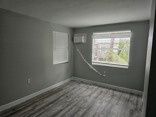 unfurnished room featuring wood-type flooring and a wall mounted AC