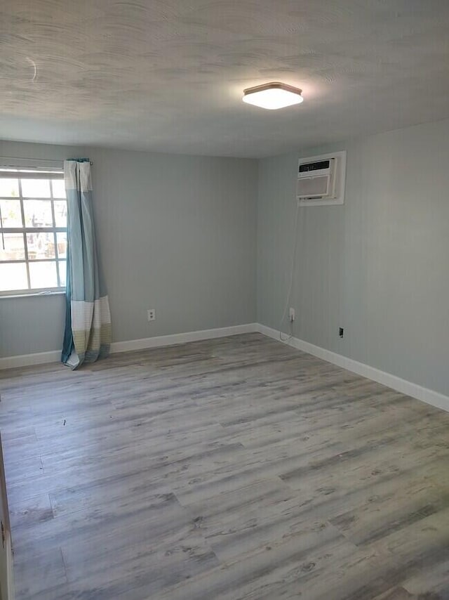 spare room featuring a wall mounted AC and light wood-type flooring