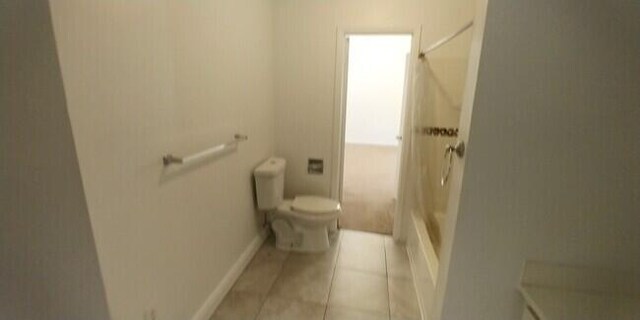 bathroom with tile patterned floors, toilet, and  shower combination