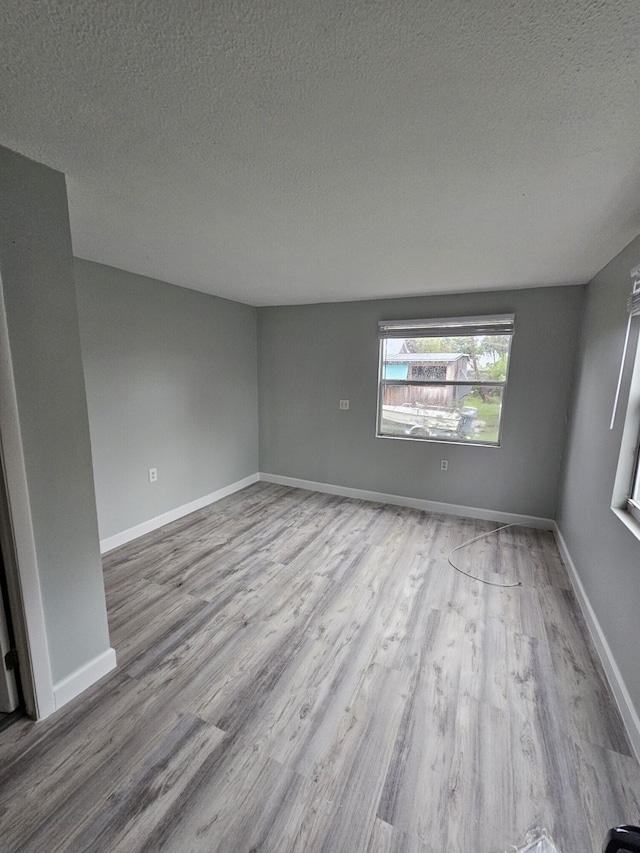 empty room with light hardwood / wood-style flooring and a textured ceiling