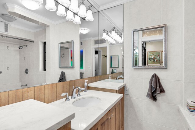 bathroom with tile walls, vanity, ornamental molding, and tiled shower