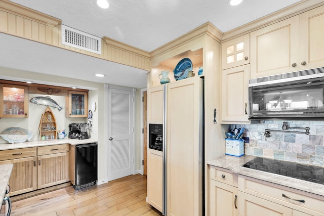 kitchen featuring light hardwood / wood-style flooring, black electric stovetop, paneled refrigerator, decorative backsplash, and beverage cooler