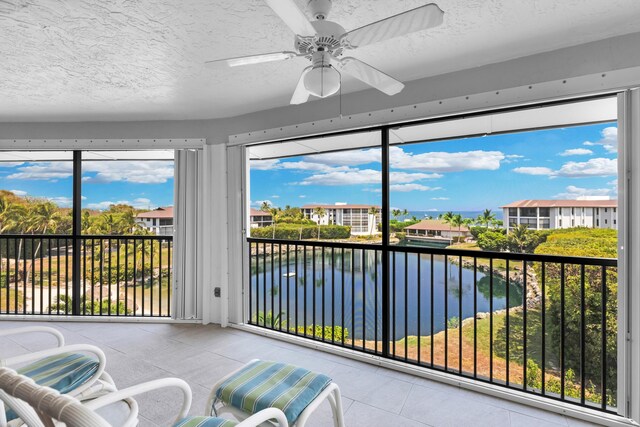 sunroom / solarium with a water view and ceiling fan