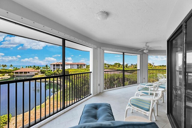 sunroom featuring ceiling fan and a water view