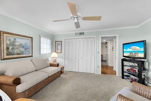 living room featuring crown molding, ceiling fan, and carpet flooring