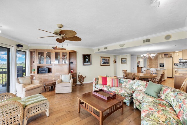 living room with crown molding, ceiling fan with notable chandelier, and light hardwood / wood-style floors