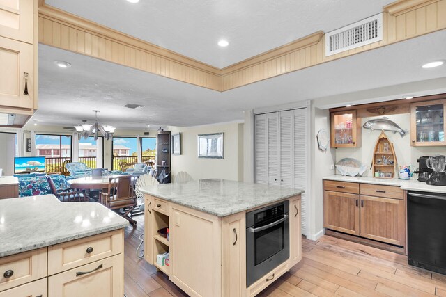 kitchen with decorative light fixtures, a center island, light wood-type flooring, dishwasher, and oven