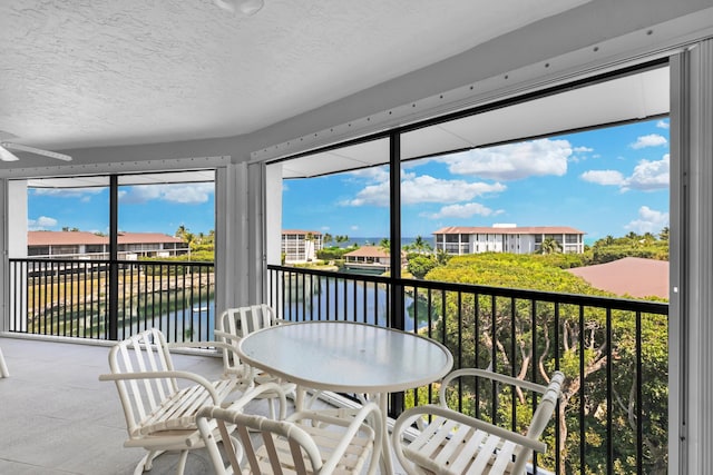 sunroom featuring a water view and ceiling fan