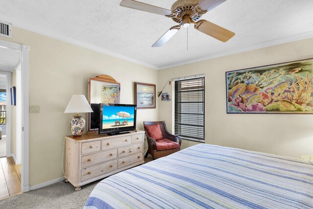 carpeted bedroom with ceiling fan, ornamental molding, and a textured ceiling