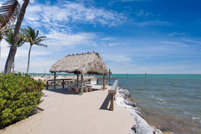 view of dock with a gazebo, a water view, and a view of the beach