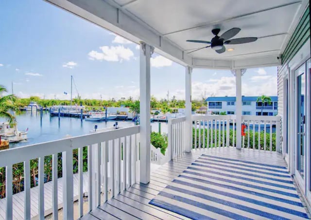 wooden terrace with a water view and ceiling fan