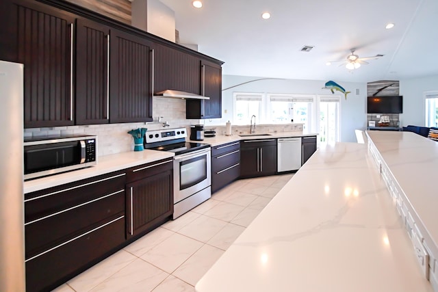 kitchen featuring appliances with stainless steel finishes, sink, decorative backsplash, ceiling fan, and dark brown cabinets