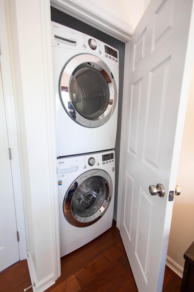 clothes washing area featuring dark wood-type flooring and stacked washing maching and dryer