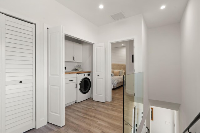 laundry area with cabinets, washer / clothes dryer, and light hardwood / wood-style flooring