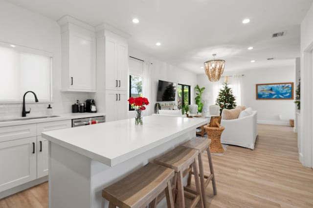 kitchen featuring pendant lighting, sink, white cabinetry, a kitchen breakfast bar, and a kitchen island