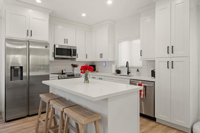 kitchen featuring white cabinetry, appliances with stainless steel finishes, sink, and a breakfast bar