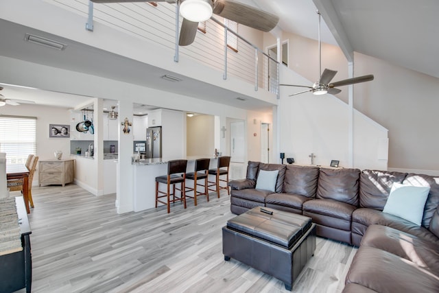 living room with high vaulted ceiling, ceiling fan, and light wood-type flooring