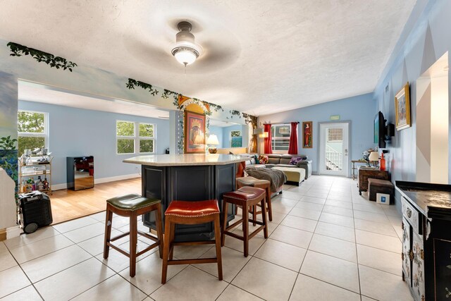 kitchen featuring a kitchen island, a breakfast bar area, a textured ceiling, and light tile patterned floors