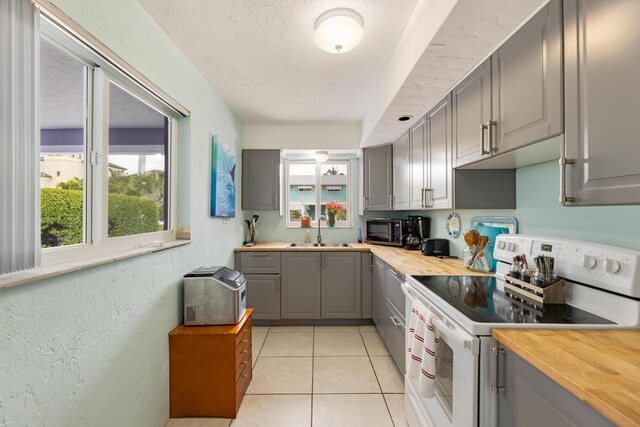 kitchen with white electric range oven, sink, butcher block countertops, a textured ceiling, and gray cabinets