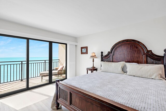 bedroom featuring a water view, access to exterior, and hardwood / wood-style floors