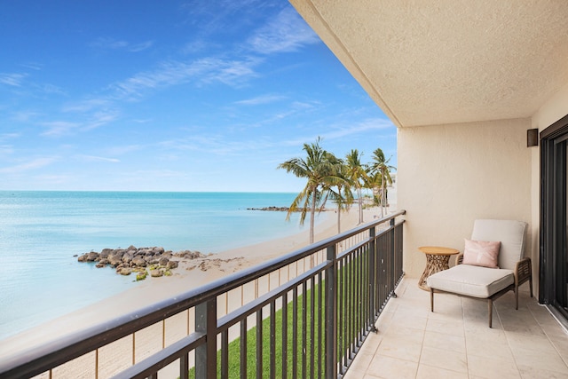 balcony featuring a view of the beach and a water view