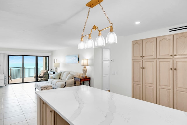 kitchen featuring light brown cabinetry, hanging light fixtures, light tile patterned floors, and light stone countertops