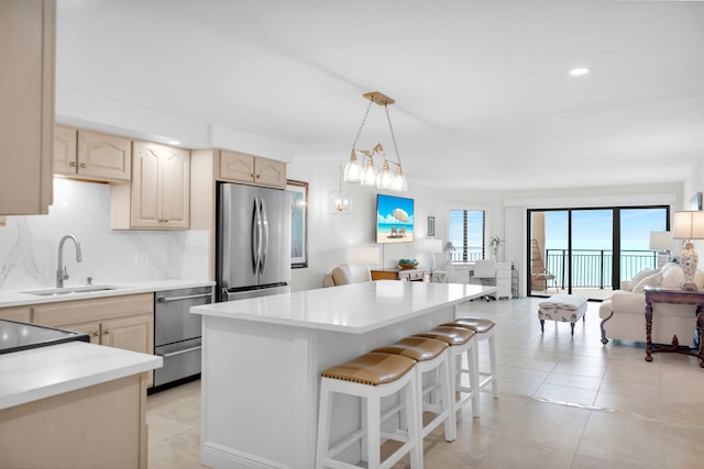 kitchen featuring sink, light tile patterned floors, appliances with stainless steel finishes, a kitchen breakfast bar, and decorative backsplash