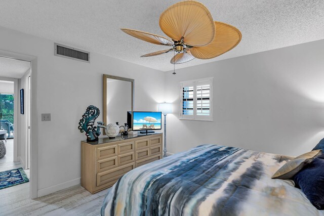 bedroom with visible vents, multiple windows, a textured ceiling, and baseboards
