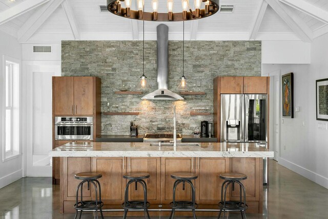 kitchen with wall chimney exhaust hood, tasteful backsplash, appliances with stainless steel finishes, and a breakfast bar area