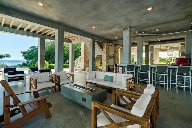 interior space featuring a water view, an outdoor living space with a fire pit, and a bar