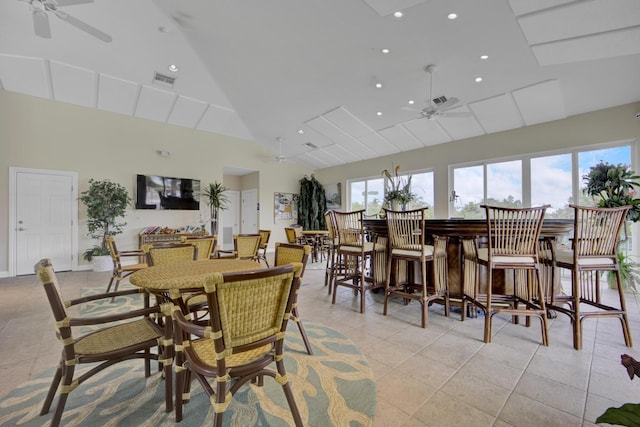 dining space with ceiling fan, bar area, high vaulted ceiling, and light tile patterned floors