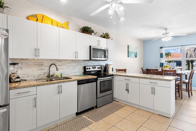 kitchen with sink, kitchen peninsula, white cabinets, stainless steel appliances, and backsplash