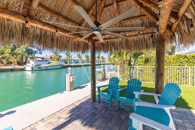 view of patio with a gazebo, a water view, a boat dock, and ceiling fan