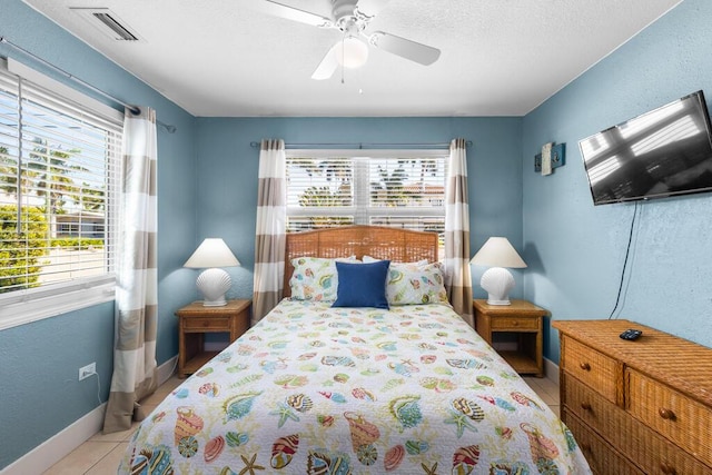 tiled bedroom with ceiling fan, multiple windows, and a textured ceiling