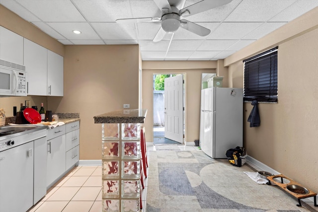 2525 Patterson Ave, Key West, FL 33040 - kitchen with white appliances, a paneled ceiling, a ceiling fan, baseboards, and white cabinets