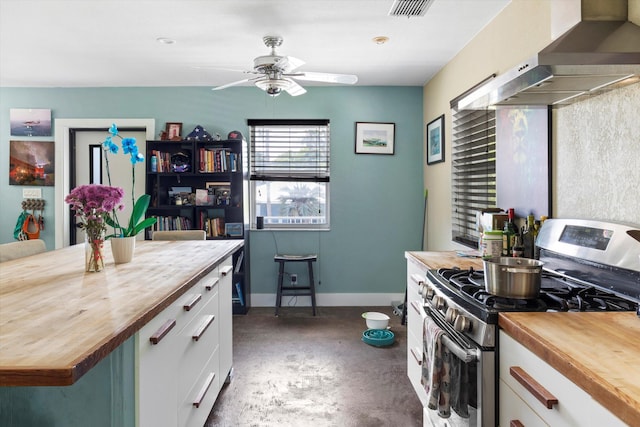 2525 Patterson Ave, Key West, FL 33040 - kitchen featuring wood counters, stainless steel gas range, wall chimney range hood, concrete floors, and white cabinetry