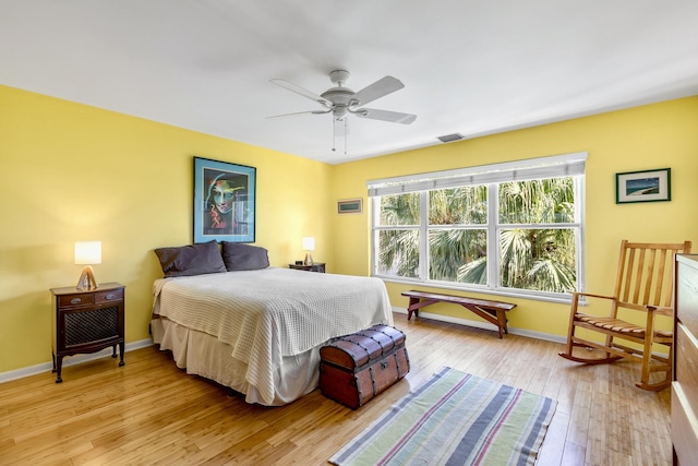 bedroom featuring light wood finished floors, a ceiling fan, visible vents, and baseboards