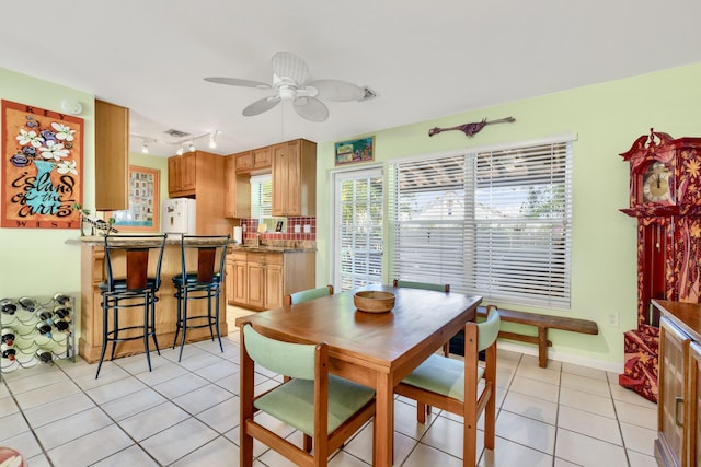 dining area with rail lighting, baseboards, a ceiling fan, and light tile patterned flooring