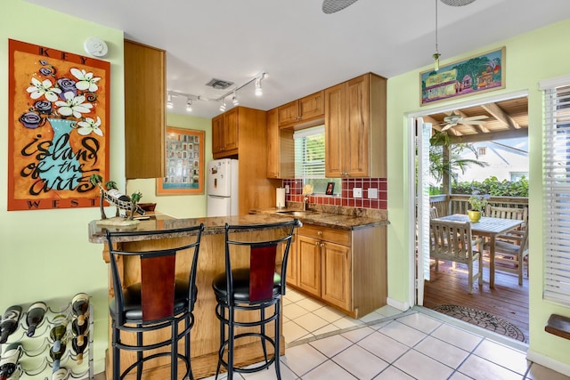 kitchen featuring tasteful backsplash, visible vents, a breakfast bar area, freestanding refrigerator, and light tile patterned flooring