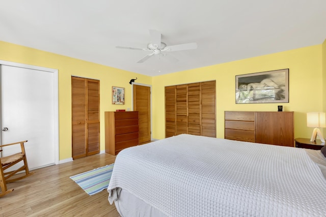 bedroom featuring baseboards, two closets, light wood-style flooring, and a ceiling fan