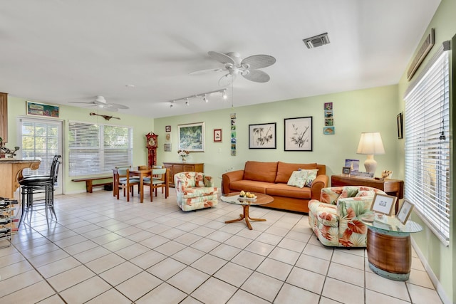 living area with light tile patterned floors, baseboards, visible vents, and a ceiling fan