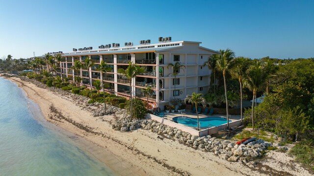 view of building exterior featuring a community pool, a beach view, and a water view