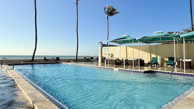 view of swimming pool with a patio area and a water view