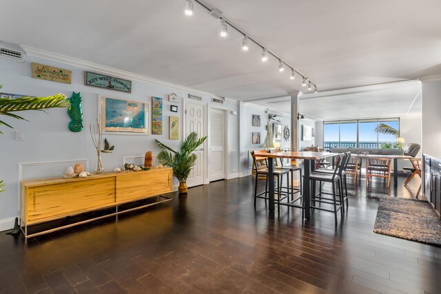 dining space with decorative columns, crown molding, dark hardwood / wood-style floors, and track lighting