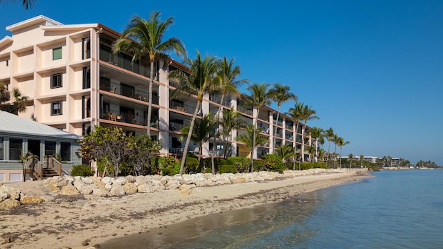 view of building exterior with a water view and a beach view